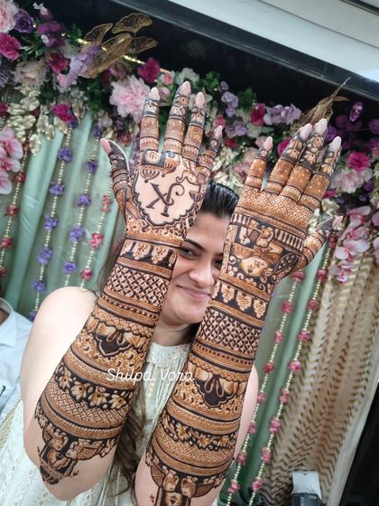 A beautiful shot displaying both arms, showing the rich, dark stain of the henna against a festive background.