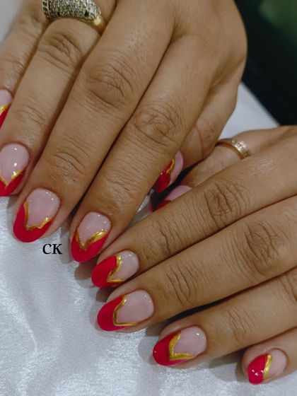 A vibrant red French manicure with a modern, angular gold chrome outline.