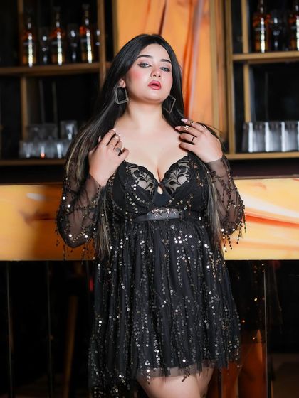 A closer shot of the model in the black party dress, focusing on her expression and the details of the outfit's neckline.