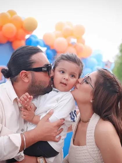 Kisses for the birthday boy! A candid moment of parental love during a second birthday party celebration.