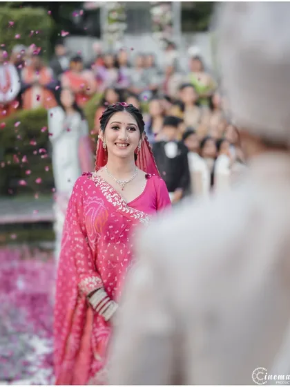 The bride's joyful expression as she walks towards the mandap, with flower petals showering down. This shot captures the anticipation and happiness of the moment.