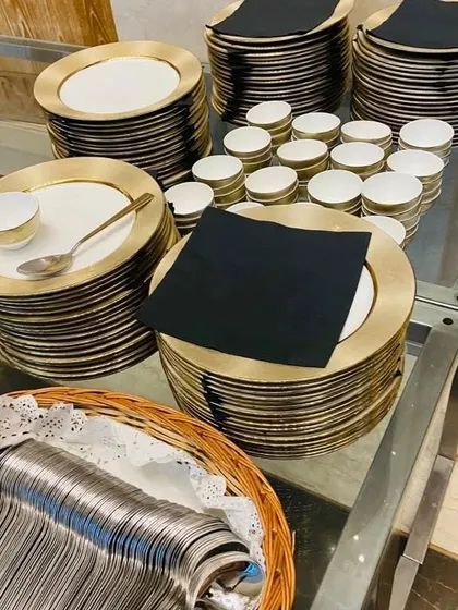 Our premium dinnerware selection includes these elegant gold-rimmed plates, paired with matching bowls and black napkins, perfect for a formal house warming or wedding reception.