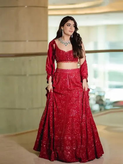 A full-length shot showcasing the sparkling details and flattering silhouette of this red lehenga.