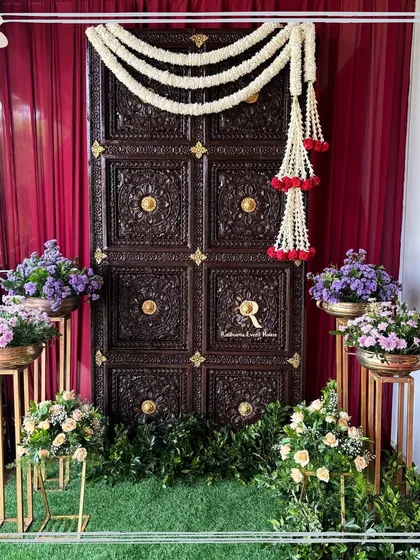 We love to blend tradition with elegance, like this stunning photo corner. A classic, intricately carved wooden door is framed by a deep red curtain and garlands of jasmine, creating a perfect backdrop that feels both timeless and grand.