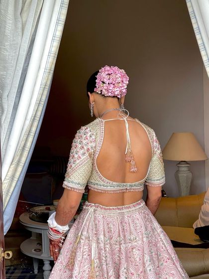 The back view of the bride's stunning pink floral bun, perfectly matching her Ejaaz Couture lehenga.
