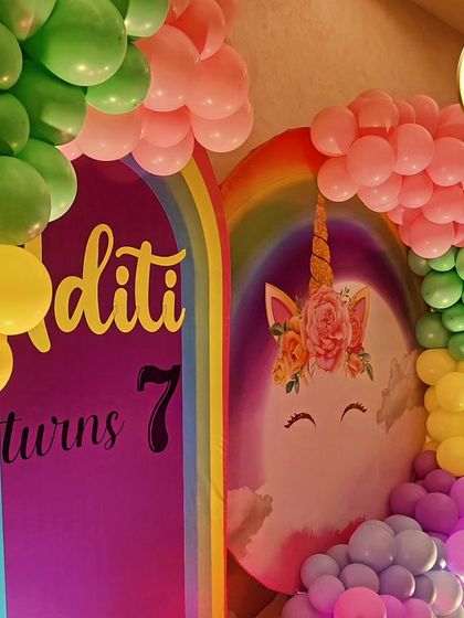 A close-up of a unicorn and rainbow-themed backdrop, showing the colorful balloon arch.