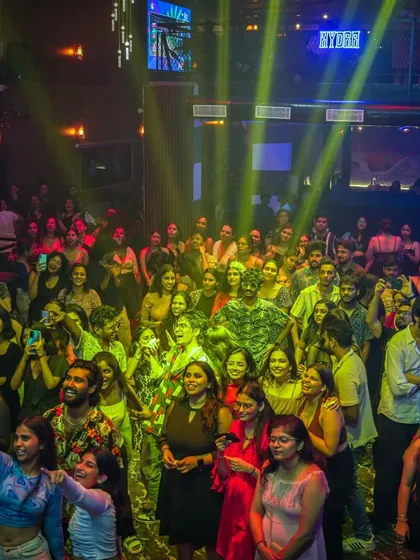 The crowd at Hydra illuminated by yellow spotlights. The lighting design is crucial for setting the mood of the party.