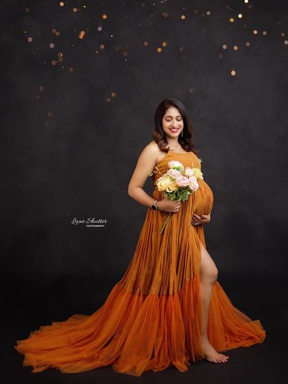 A lovely solo portrait in a burnt orange gown, with the mom-to-be holding a bouquet of flowers.