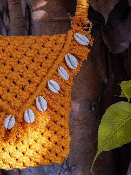 A detailed close-up of the sea shell trim on my mustard yellow macrame bag. I source these shells myself to ensure they add the perfect finishing touch. This is a great example of how I can customize your bag to make it uniquely yours.