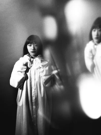 An experimental film shot using double exposure or a reflection. The ghostly second image of the model adds a layer of complexity and a dreamlike narrative.