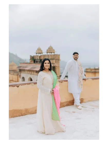 A lovely portrait with the bride in the foreground and the groom behind, set against the stunning backdrop of Amer Fort.