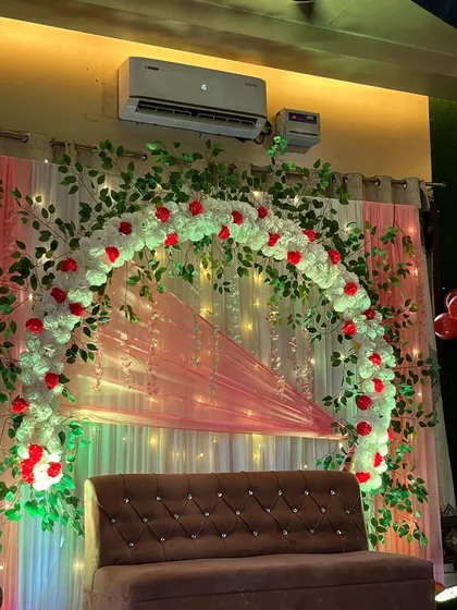 A clear shot of the home engagement stage, featuring a brown tufted sofa and a classic red and white floral arch.