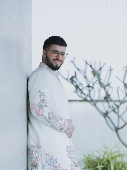 A happy groom on his wedding day. This look features natural makeup that enhances his features while looking effortless, paired with a modern hairstyle and glasses.