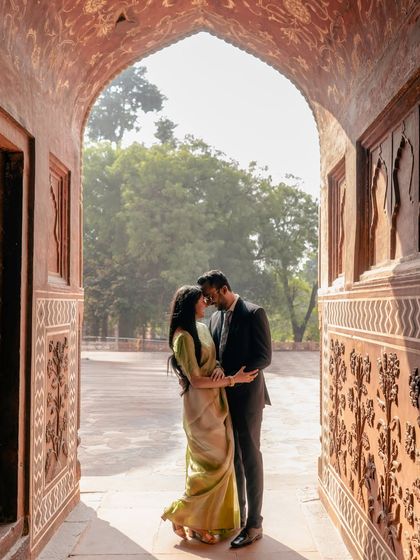 An intimate embrace framed by a beautifully carved doorway. The soft morning light filters through, creating a warm and romantic atmosphere for this pre-wedding portrait.