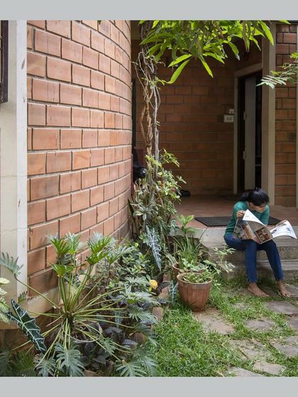 A resident enjoys a quiet moment reading on the steps, demonstrating how the house provides small, comfortable nooks for daily life.