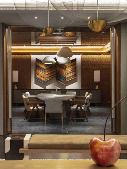 A view into the jewel-box dining room from the lobby. A sculptural cherry art piece in the foreground adds a playful contrast to the sophisticated dining space beyond.