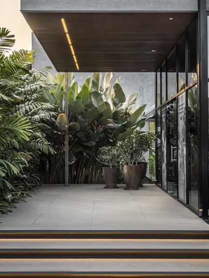 The entrance pathway to the marketing office is lined with lush tropical plants, creating a welcoming and refreshing transition from the outside.