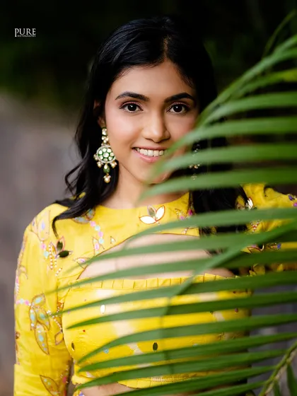 A peek-a-boo portrait of the bride during her Mehndi ceremony. The green leaf adds a natural and creative frame to her beautiful smile.