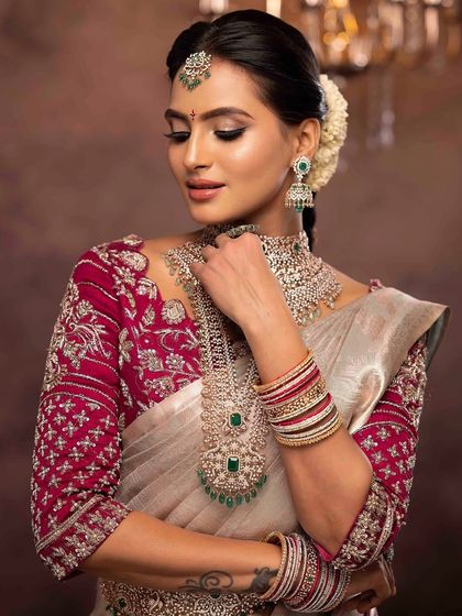 A close-up showcasing the detailed eye makeup and how it complements the emeralds in her diamond jewelry set. The hairstyle is a classic bun adorned with fresh flowers.