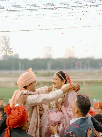 A fun and celebratory moment during the varmala ceremony. The outdoor setting, with the open racecourse and fairy lights, provides a spacious and festive atmosphere.