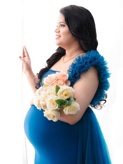 Looking out as if towards the future. This portrait captures a moment of hopeful anticipation, with the mother-to-be holding a bouquet against a bright, airy background.