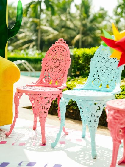 Ornate, vintage-style garden chairs painted in bright pastel pink and blue. This eclectic mix of furniture styles was a key part of the Coachella theme.