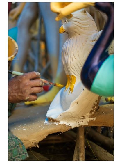 An artisan paints the feathers of an eagle, the vahana (vehicle) for one of the deities, showcasing the attention to detail in every element of the tableau.