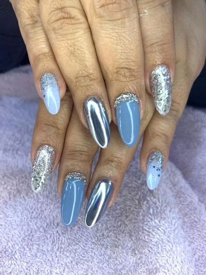 A cool-toned set featuring a mix of blue-grey polish, silver glitter, and silver chrome accent nails.