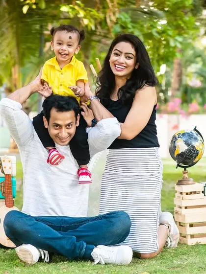 A complete family portrait from an outdoor pre-birthday shoot, with the family sitting together on the grass.