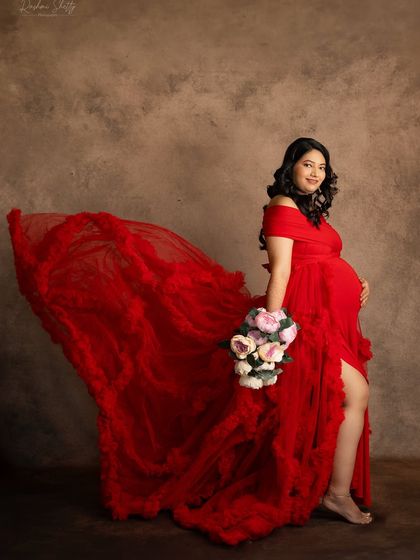 Adding a flowing train and a bouquet of flowers brings a sense of movement and romance to this studio portrait. The vibrant red gown stands out beautifully against the textured backdrop.