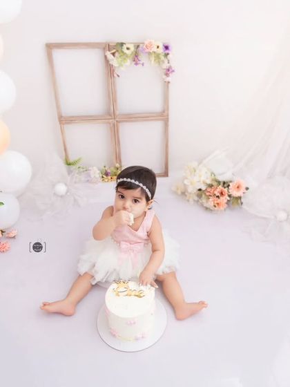 A tiny taste of sweetness. This baby girl enjoys a bite of her beautiful birthday cake in a light and airy studio setting.