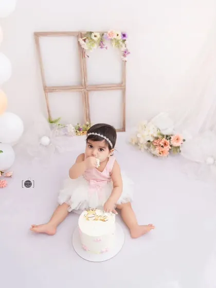A tiny taste of sweetness. This baby girl enjoys a bite of her beautiful birthday cake in a light and airy studio setting.