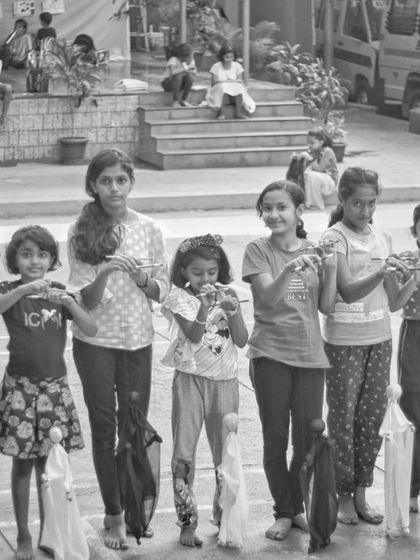 A group of young puppeteers from a Bimba summer camp. They are all holding their simple cloth marionettes, ready for their first group performance.