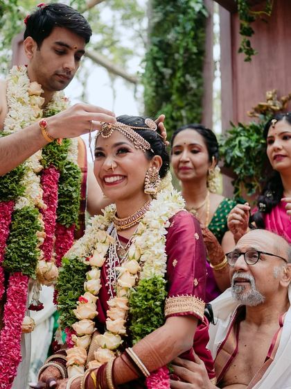 The bride's radiant smile as her groom performs a key wedding ritual, surrounded by the love of their families.