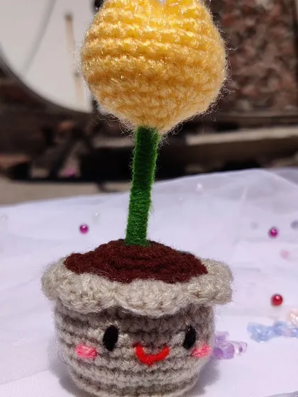 A photo dump of various small crochet items, including this cute yellow tulip in a smiley pot.