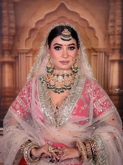 A classic bridal portrait, with the bride looking confidently at the camera, showcasing her full makeup and jewelry.