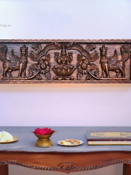 This 38-inch wall panel shows Goddess Mahalakshmi flanked by two standing Kamadhenu (divine cows). Here, it is styled above a traditional console table, demonstrating its use in a pooja or prayer space.