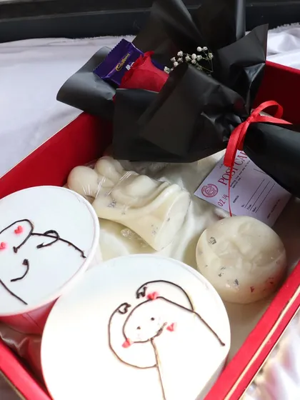 A close-up of the "Decadent Love" hamper, showing the cute dessert tubs, candles, and a mini rose bouquet.