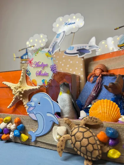 This shot highlights the personalized acrylic nameplate for 'Aadiya Shakti' amidst a collection of dolphins, starfish, and other sea creatures.