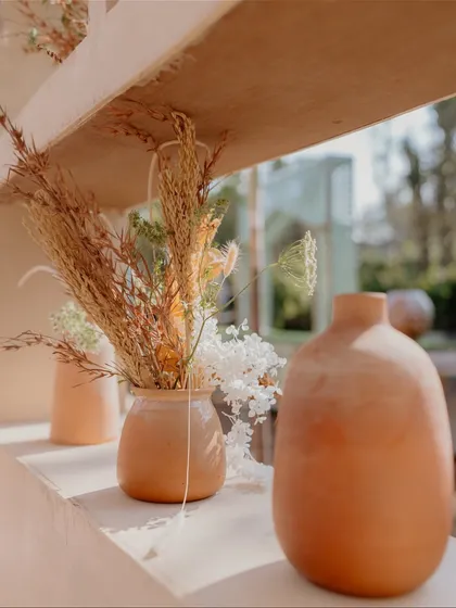 A detailed shot of the rustic floral arrangements, featuring dried wheat and wildflowers in terracotta vases, perfectly capturing the 'Desert Oasis' aesthetic.