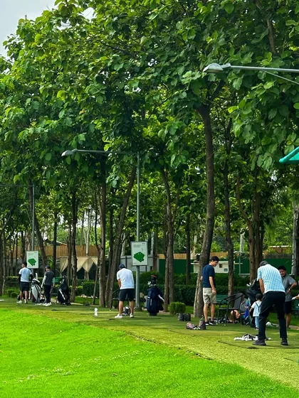Golfers line the range on a weekend, with some taking a break while others are in mid-swing.