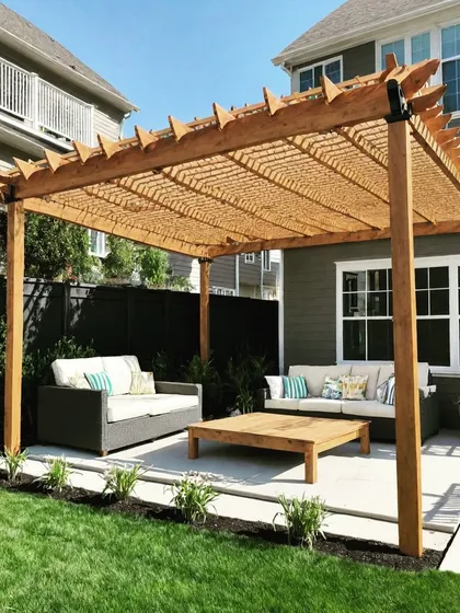 A large wooden pergola with a woven top cover, creating a shaded lounge area in the backyard. The design is perfect for housing multiple sofas and a coffee table for entertaining.