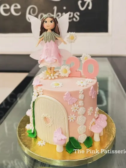 An enchanting fairy-themed cake for a 20th birthday. The design includes a fairy house door, mushrooms, flowers, and a beautifully detailed, handcrafted fairy topper.