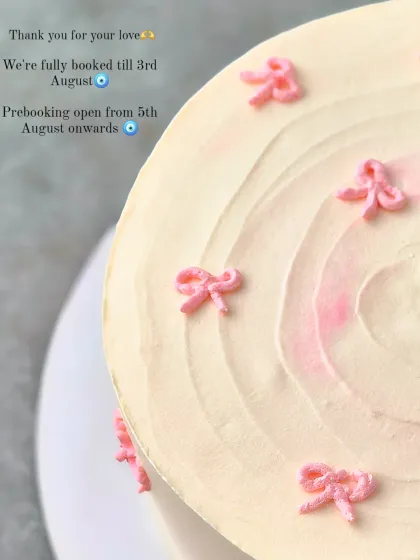 A close-up of the piped bows and swirled top of the minimalist pink cake.