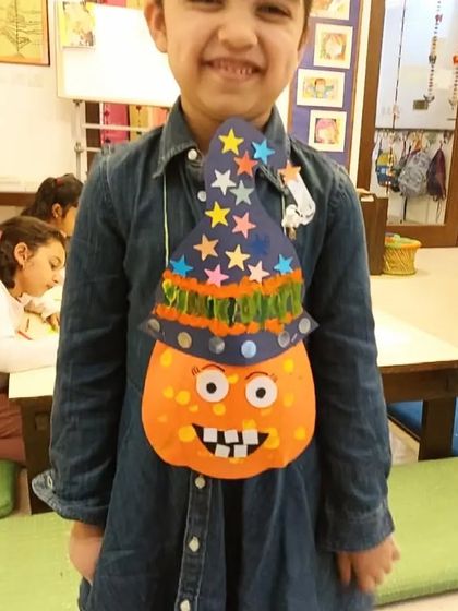 This student is all smiles with his Halloween goody bag, shaped like a jack-o'-lantern with a wizard hat. It is both a craft and a treat holder.