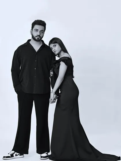 A modern and stylish black and white couple portrait taken in my studio. The clean background and classic posing highlight the couple's connection and individual style, showcasing a timeless yet contemporary look.