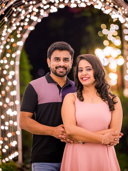 A classic, smiling portrait of a couple framed by the beautiful arch of fairy lights.