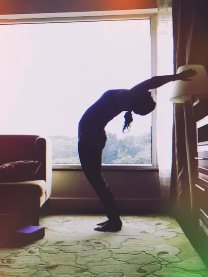 Taking my practice on vacation. Here I'm using a wall and a lamp for support in a deep backbend. You can find ways to stretch and move anywhere.