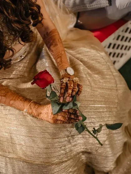 A single red rose held by the bride, her beautifully hennaed hands providing a stunning contrast. A simple, romantic, and elegant shot.