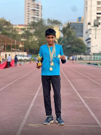 This young athlete proudly displays his medals and trophy on the track. This is what happens when potential meets dedication.